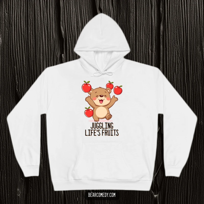 Funny hoodie illustration of a bear with a look of intense concentration and joy, juggling three red apples.