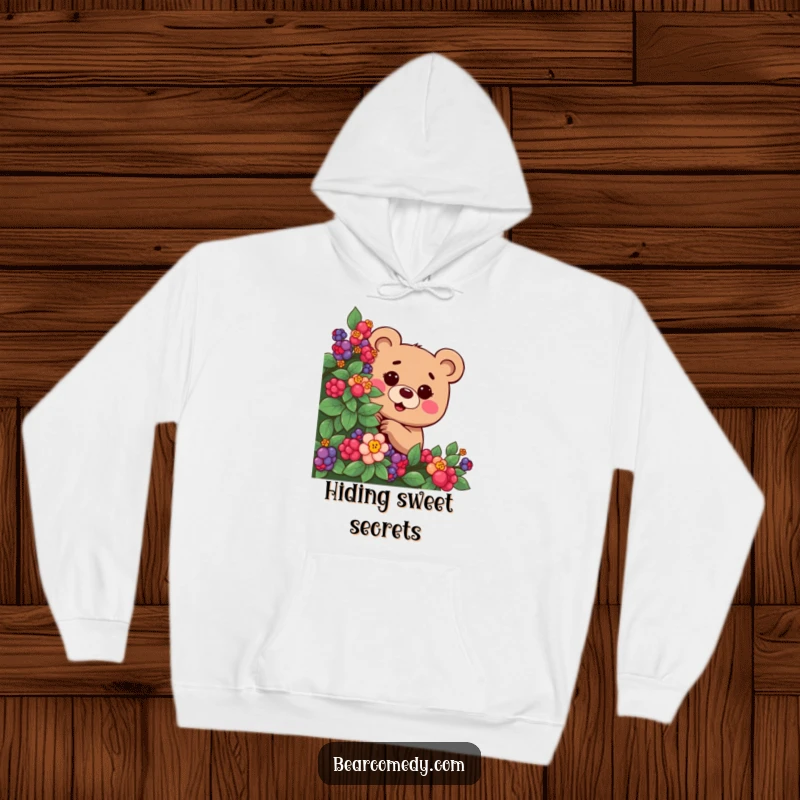 Funny hoodie depicting a bear with a mischievous twinkle, playfully peeking from behind a berry bush, embodying playful secrecy.