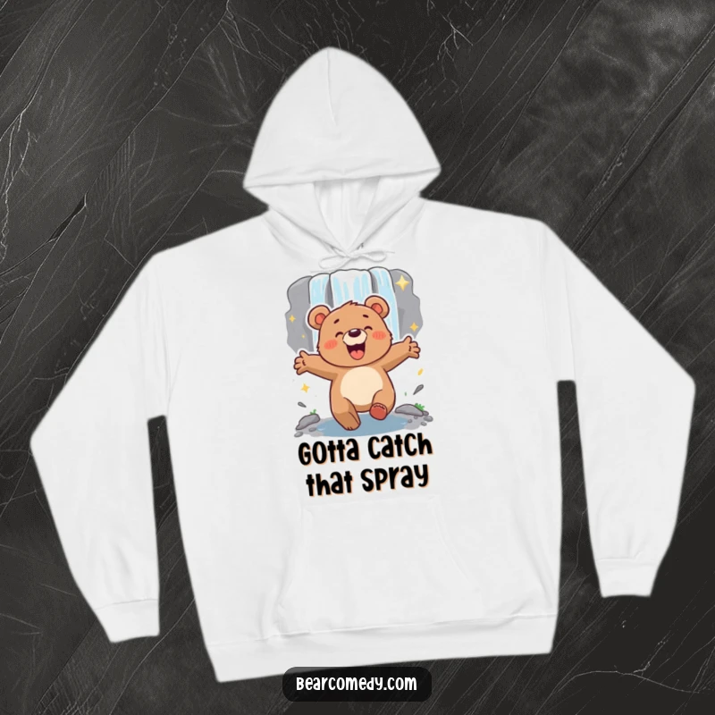 Funny energetic bear with arms outstretched, lumbering excitedly towards a sparkling waterfall, a cozy hoodie for adventurers.