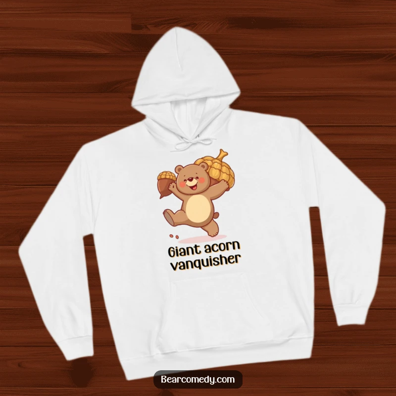 Funny hoodie design: A bear joyfully kicks a large, bouncing acorn, embodying playful energy and outdoor fun.