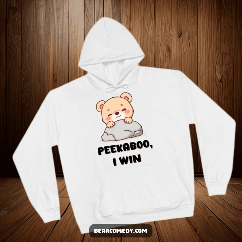 Funny bear character with a mischievous wink peeking from behind a rock on a cozy hoodie, for playful comfort.